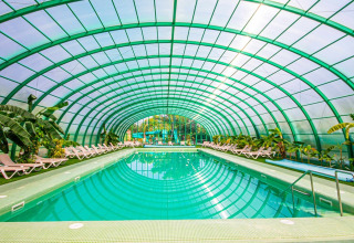 Overdækket swimmingpool med liggestole og tropiske planter på Camping & Resort La Torre del Sol, Costa Dorada.