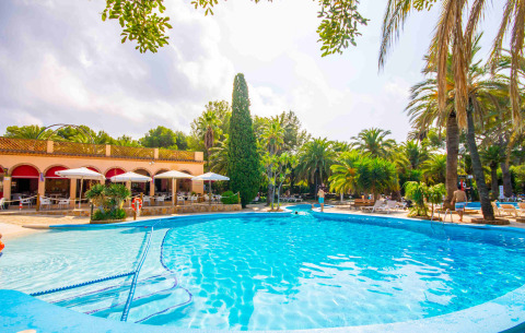 Camping & Resort La Torre del Sol sur la Costa Dorada avec piscine, palmiers et terrasse ombragée pour glamping.