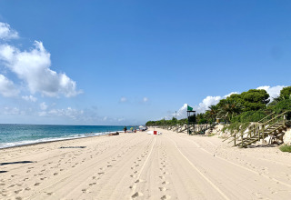 Vue de la plage au Camping & Resort La Torre del Sol - Safaritenten Costa Dorada, sous un ciel bleu clair.