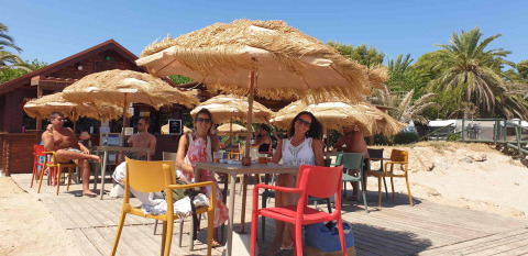 Gäste entspannen sich im Schatten am Strandcafé im Camping & Resort La Torre del Sol – Safaritenten Costa Dorada.