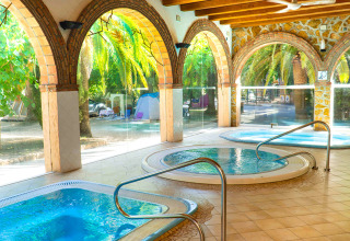 Zona de spa interior con jacuzzis y vistas a palmeras en Camping & Resort La Torre del Sol, Costa Dorada.