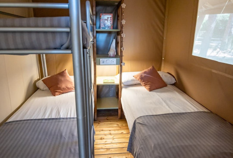Binnenaanzicht van een luxe safaritent op Camping & Resort La Torre del Sol met bedden en stapelbed.
