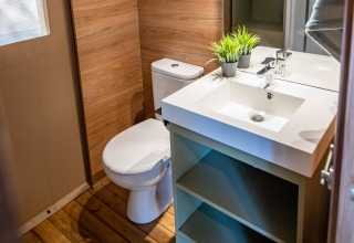 Baño moderno en tienda safari del Camping & Resort La Torre del Sol, Costa Dorada, con detalles en madera.