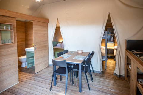 Interieur van safaritent op Camping & Resort La Torre del Sol met eethoek en kleine keuken zichtbaar.