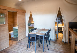Vista interior del glamping en Camping & Resort La Torre del Sol con zona de comedor y cocina equipada.