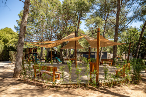 Legeplads og siddeområde med bænke under solsejl ved Camping & Resort La Torre del Sol, Costa Dorada.