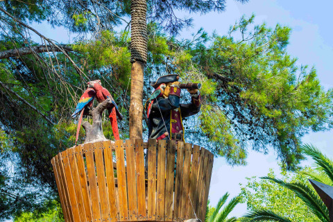 Tour de guet avec une statue de pirate et des perroquets dans les arbres au Camping & Resort La Torre del Sol, Costa Dorada.
