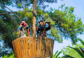 Uitkijktoren met piratenbeeld en papegaaien in de bomen bij Camping & Resort La Torre del Sol, Costa Dorada.
