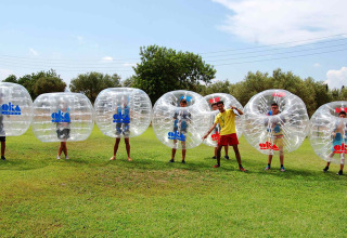 Niños jugando fútbol burbuja en Camping & Resort La Torre del Sol, Costa Dorada, en un día soleado.