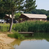Glamping accommodation at a lakeside with tent lodges, parking, and greenery at Camping Heidekamp.