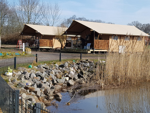 Glamping accommodatie bij Camping Heidekamp met lodges en pods in Noordrijn-Westfalen naast een vijver.