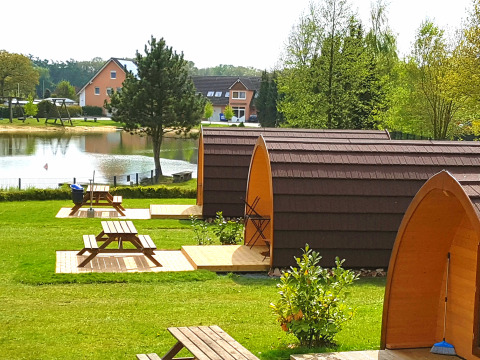 Sistemazioni glamping al Camping Heidekamp, lodge e pod moderni vicino a un laghetto in Renania Settentrionale.
