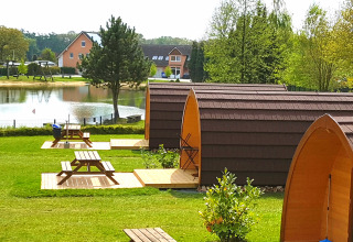 Glamping accommodations at Camping Heidekamp, stylish lodges and pods near a pond in lush Nordrhein-Westfalen.