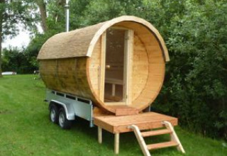 Lodge di legno a forma di botte su rimorchio, ideale per glamping a Camping Heidekamp nella Renania Settentrionale.