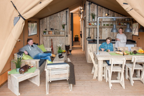 Gezin geniet van luxe glamping in een lodge op Camping Heidekamp met moderne houten inrichting.
