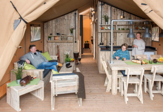 Gezin geniet van luxe glamping in een lodge op Camping Heidekamp met moderne houten inrichting.