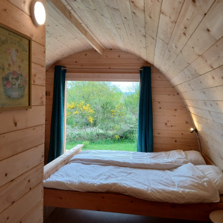 Indretning af glamping-pod på Junora - Pods Haute Vienne med trævægge, dobbeltseng og naturudsigt.