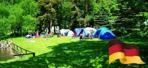 Camping Safritop am Mühlenteich en Rhénanie-Palatinat avec tentes, pelouse verte et drapeau allemand.