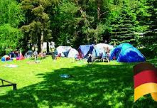 Camping Safritop am Mühlenteich in Rijnland-Palts met tenten op grasveld en een Duitse vlag in beeld.