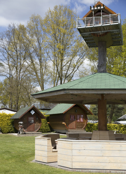 Glamping singular en Kampeerbos de Simonshoek con cabañas de barril y una casa en el árbol elevada.