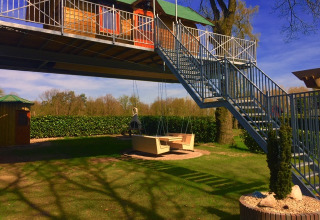 Alojamiento glamping en casa del árbol con escaleras metálicas y columpio en Kampeerbos de Simonshoek.