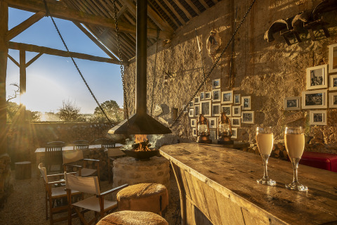 Rustikale Glamping-Bar bei Kimaro Farmhouse - Safaritenten Bourgogne mit Kamin, Holztresen und Deko.