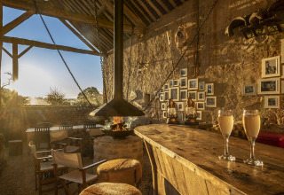 Rustieke glampingbar bij Kimaro Farmhouse - Safaritenten Bourgogne met open haard en warm zonlicht.