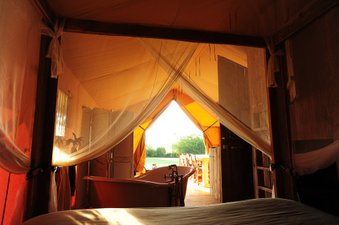 Zicht vanuit een luxueuze glampingtent met bad bij Kimaro Farmhouse Safaritenten Bourgogne bij zonsondergang.
