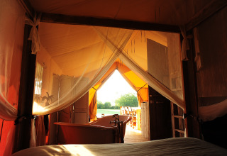 Vue depuis une tente de glamping de luxe avec baignoire au Kimaro Farmhouse Safaritenten Bourgogne au coucher du soleil.