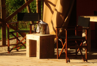 Coin salon extérieur de Kimaro Farmhouse Safaritenten Bourgogne avec fauteuils, table et boissons.