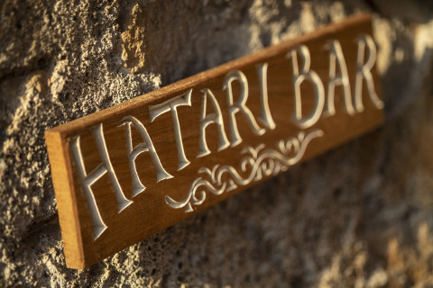 Træskilt med teksten 'Hatari Bar' monteret på en stenvæg ved Kimaro Farmhouse - Safaritenten Bourgogne.