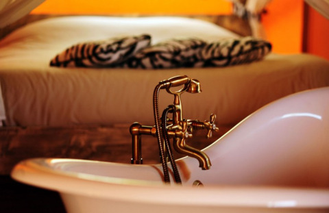 Intérieur de Kimaro Farmhouse - Safaritenten Bourgogne avec baignoire autoportante et lit confortable.