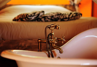 Innenraum von Kimaro Farmhouse - Safaritenten Bourgogne mit freistehender Badewanne und gemütlichem Bett.