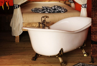 Baignoire sur pieds élégante à côté d’un lit dans une tente safari de glamping au Kimaro Farmhouse en Bourgogne.