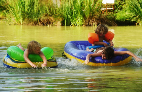 Kinder spielen auf aufblasbaren Booten im See bei Kimaro Farmhouse - Safaritenten Bourgogne Campingplatz.