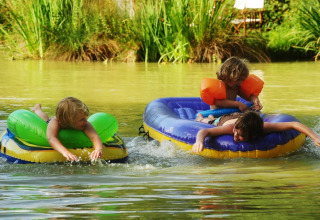 Enfants jouant sur des bouées sur un lac au Kimaro Farmhouse - Safaritenten Bourgogne, camping glamping.