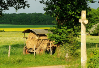 Zicht op velden aan Kimaro Farmhouse - Safaritenten Bourgogne met hooikar en veldkruis, campinggevoel.