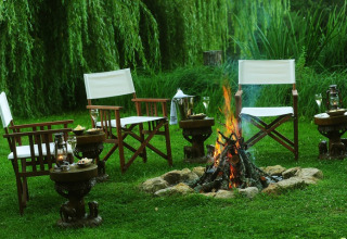 Glamping setup with cozy chairs, a firepit, and greenery at Kimaro Farmhouse - Safaritenten Bourgogne.
