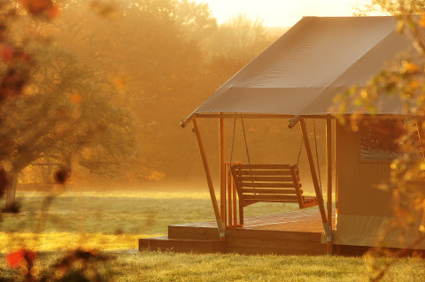 Glamping at Kimaro Farmhouse - Safaritenten Bourgogne, sunrise view with porch swing and scenic nature.