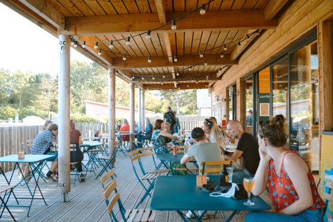 Udendørs terrasse ved Huttopia Les Falaises - Glamping Normandië, med gæster der nyder solen.