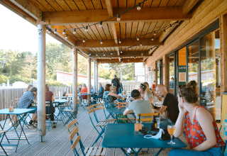 Terraza exterior en Huttopia Les Falaises - Glamping Normandië con huéspedes comiendo y relajándose.