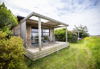 Hébergement glamping en cabane boisée à Huttopia Les Falaises, Normandie, entouré de verdure et nature.