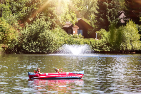 To børn padler i en oppustelig båd på en sø ved Camping en Vakantiepark Teichmann - Glamping Hessen.