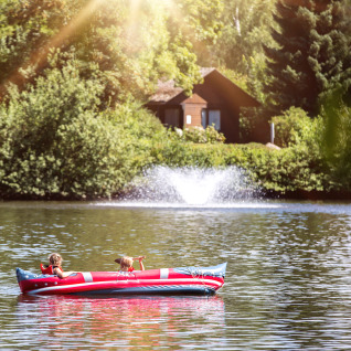 Zwei Kinder paddeln in einem Schlauchboot auf einem See bei Camping en Vakantiepark Teichmann - Glamping Hessen.