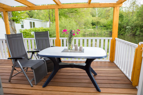 Overdækket terrasse med bord, stole, blomster og udsigt over grøn natur på Camping en Vakantiepark Teichmann.