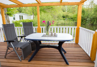 Overdækket terrasse med bord, stole, blomster og udsigt over grøn natur på Camping en Vakantiepark Teichmann.