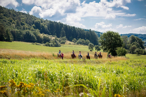 Personas a caballo cruzando verdes prados en Camping en Vakantiepark Teichmann - Glamping Hessen.