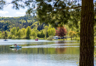 Scenic lake view at Camping en Vakantiepark Teichmann - Glamping Hessen with paddle boats and lush greenery.