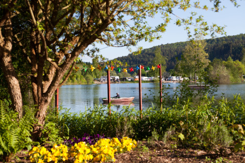Vista al lago en Camping en Vakantiepark Teichmann en Hessen con flores de verano y botes en el agua.