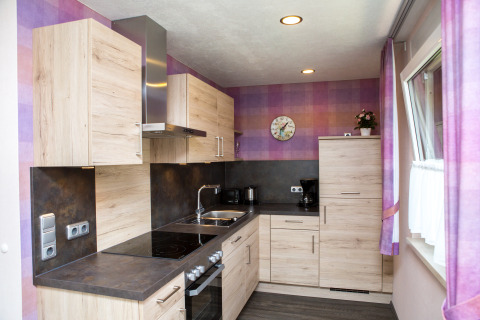 Moderne glampingkeuken bij Camping en Vakantiepark Teichmann in Hessen met houten kasten en paarse muren.